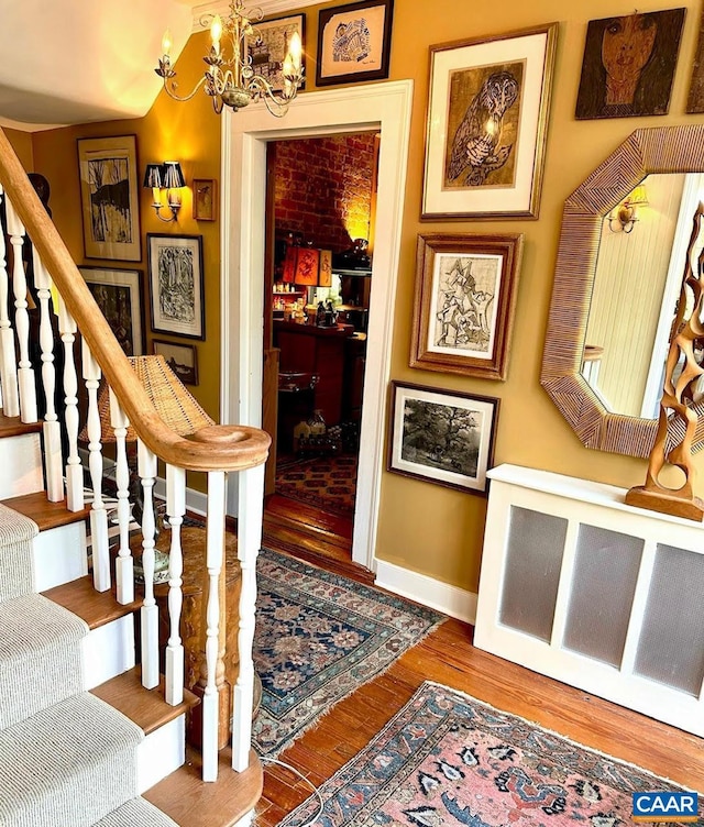 stairway with a chandelier, baseboards, and wood finished floors