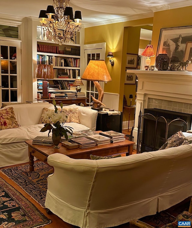 sitting room with a tile fireplace, a chandelier, and crown molding