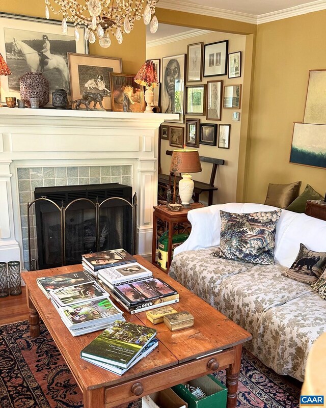 living room with ornamental molding, wood finished floors, a chandelier, and a fireplace