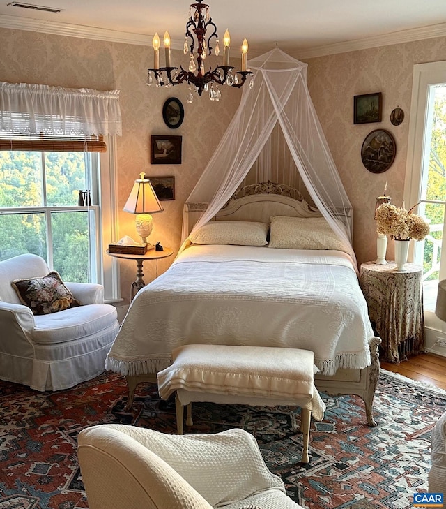 bedroom featuring wallpapered walls, wood finished floors, an inviting chandelier, and crown molding