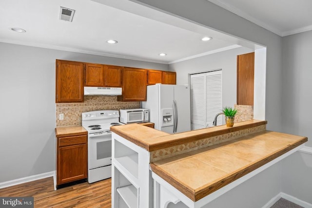 11260 Girven Ct, Fredericksburg, VA 22407 - kitchen featuring white appliances, under cabinet range hood, crown molding, decorative backsplash, and brown cabinetry