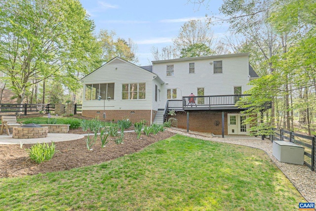rear view of property with an outdoor fire pit, a wooden deck, stairs, a sunroom, and a patio area
