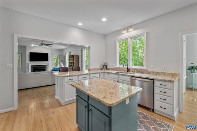 kitchen with dishwasher, white cabinetry, a center island, a sink, and ceiling fan