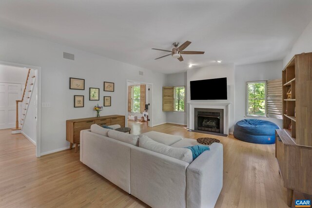 living area featuring light wood-type flooring, ceiling fan, stairs, a fireplace with flush hearth, and recessed lighting