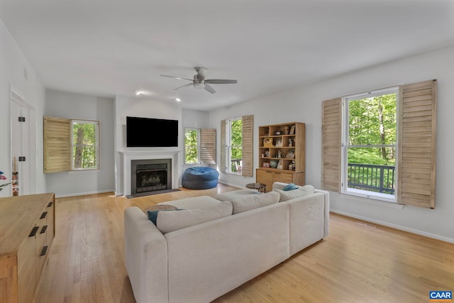 living room featuring light wood finished floors, ceiling fan, healthy amount of natural light, and baseboards