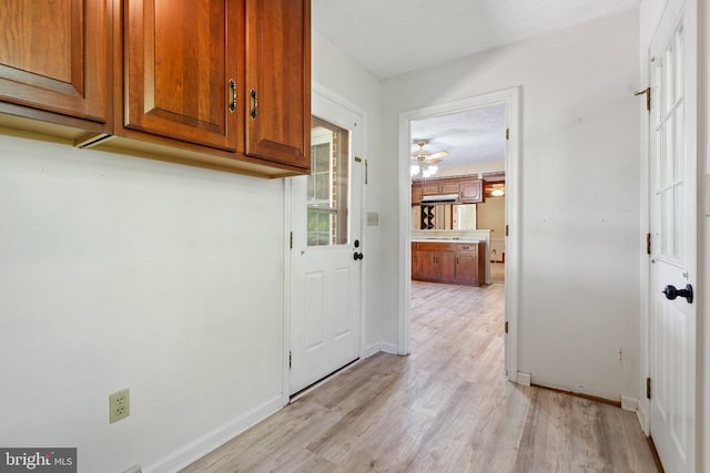 washroom featuring baseboards, light wood-type flooring, and cabinet space
