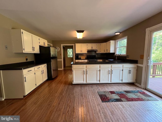  - kitchen with black electric range, freestanding refrigerator, dark wood-type flooring, dark countertops, and white cabinets