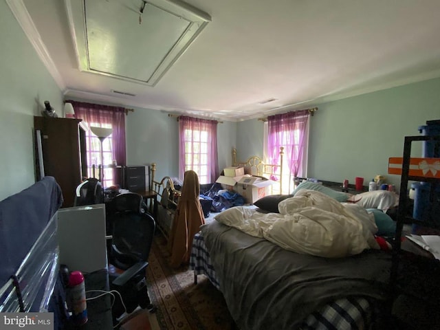  - bedroom with attic access, wood finished floors, and crown molding
