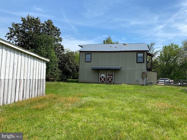  - rear view of property with a yard, metal roof, and central AC unit