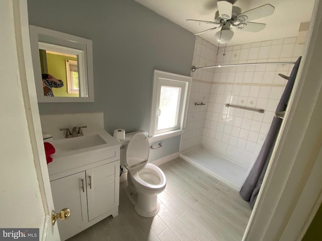  - bathroom featuring tiled shower, vanity, ceiling fan, toilet, and baseboards