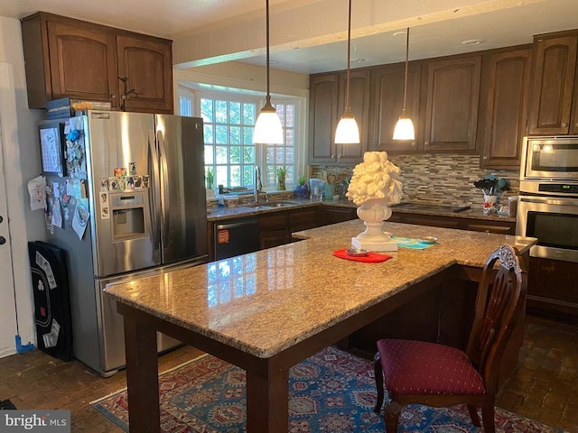  - kitchen featuring appliances with stainless steel finishes, a sink, light stone countertops, tasteful backsplash, and decorative light fixtures