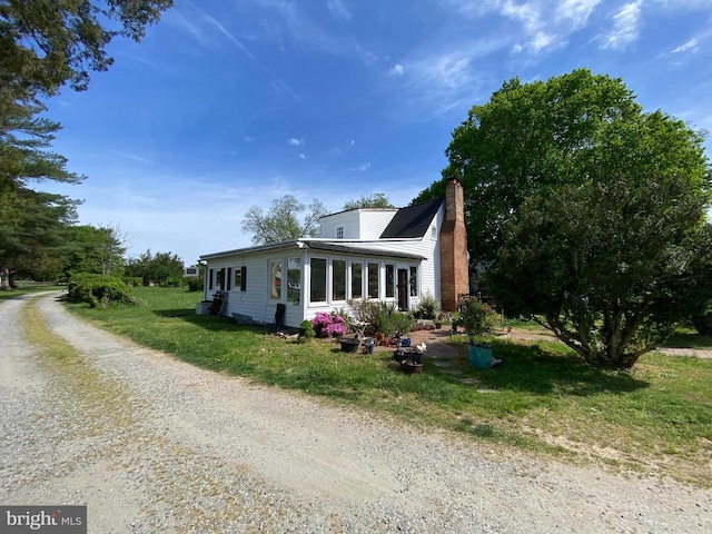  - view of front of house with a chimney and a front lawn