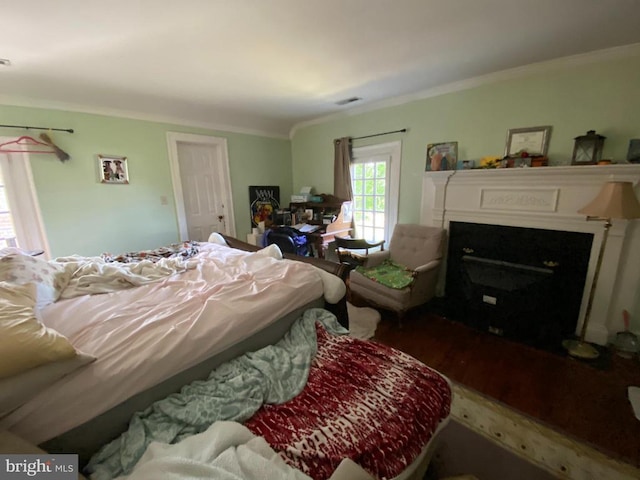 - bedroom with ornamental molding, wood finished floors, and a fireplace