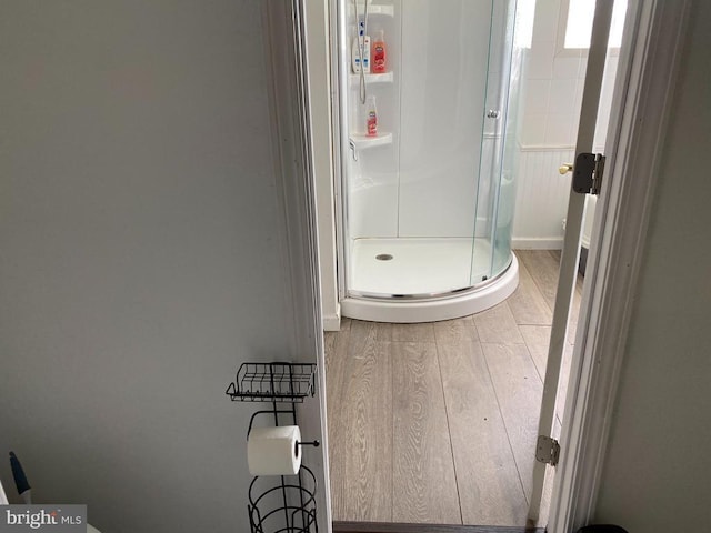  - full bath with wood finished floors and a stall shower