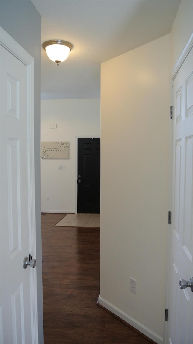 corridor with baseboards and wood finished floors