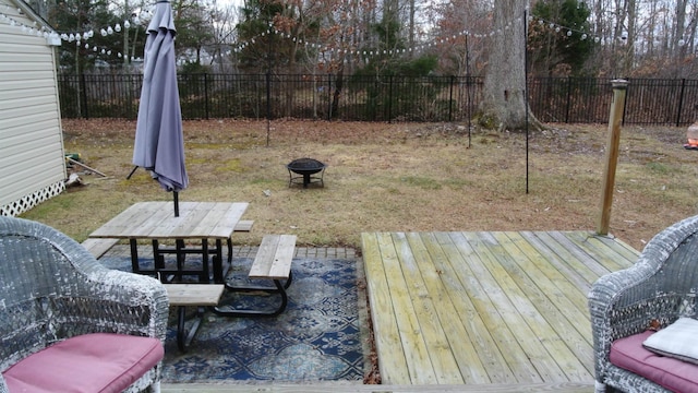 wooden deck featuring outdoor dining area, a fenced backyard, and a fire pit