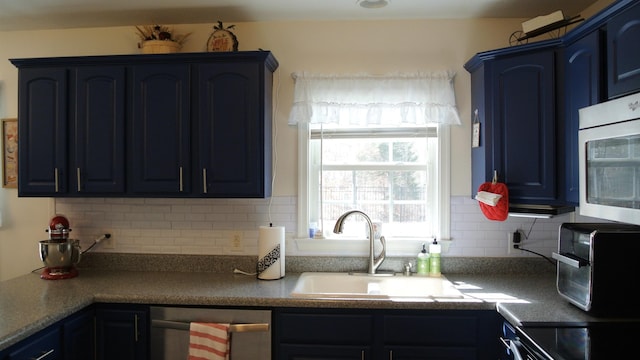 kitchen featuring blue cabinetry, backsplash, a sink, and appliances with stainless steel finishes