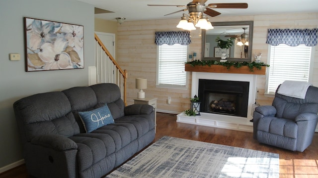 living room with a fireplace with raised hearth, stairway, wood finished floors, and wooden walls