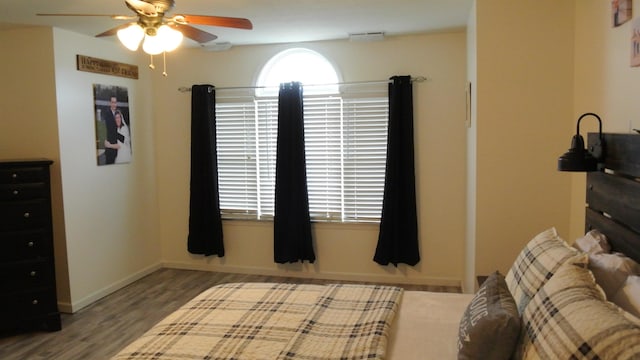 bedroom featuring a ceiling fan, visible vents, baseboards, and wood finished floors