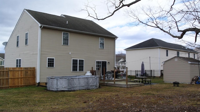 rear view of property with a fenced in pool, fence, a deck, and an outdoor structure