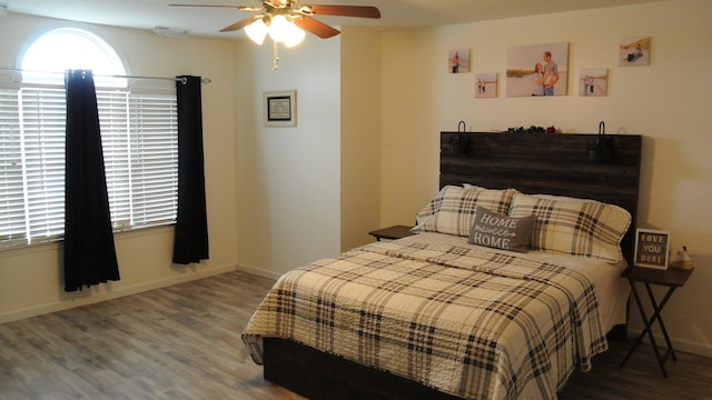 bedroom with ceiling fan, wood finished floors, and baseboards