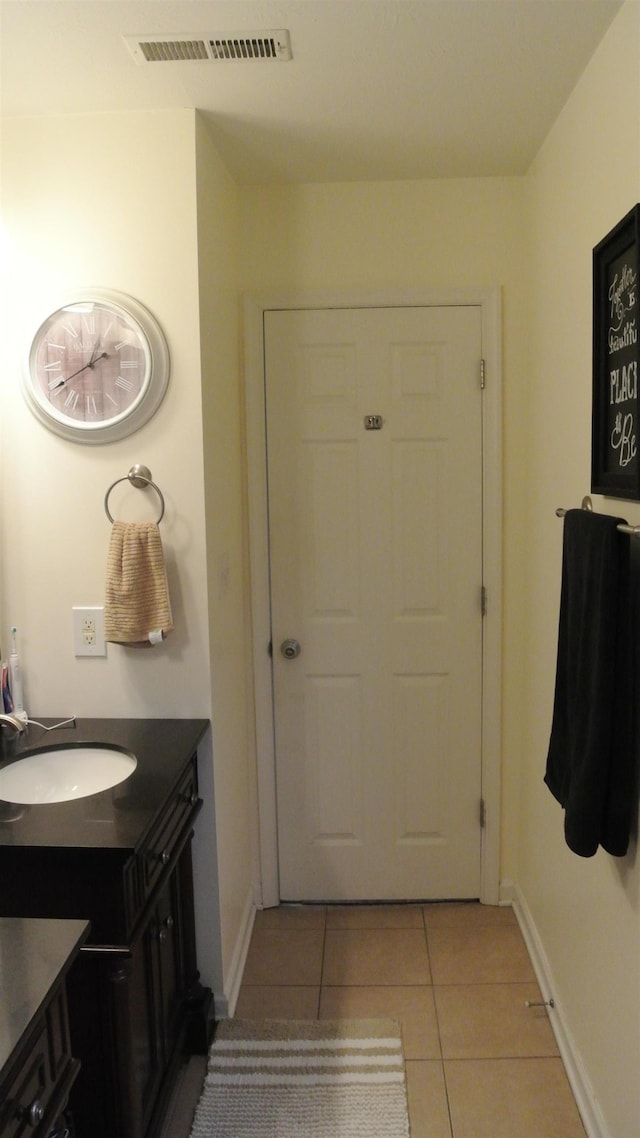 entryway with light tile patterned floors, a sink, visible vents, and baseboards