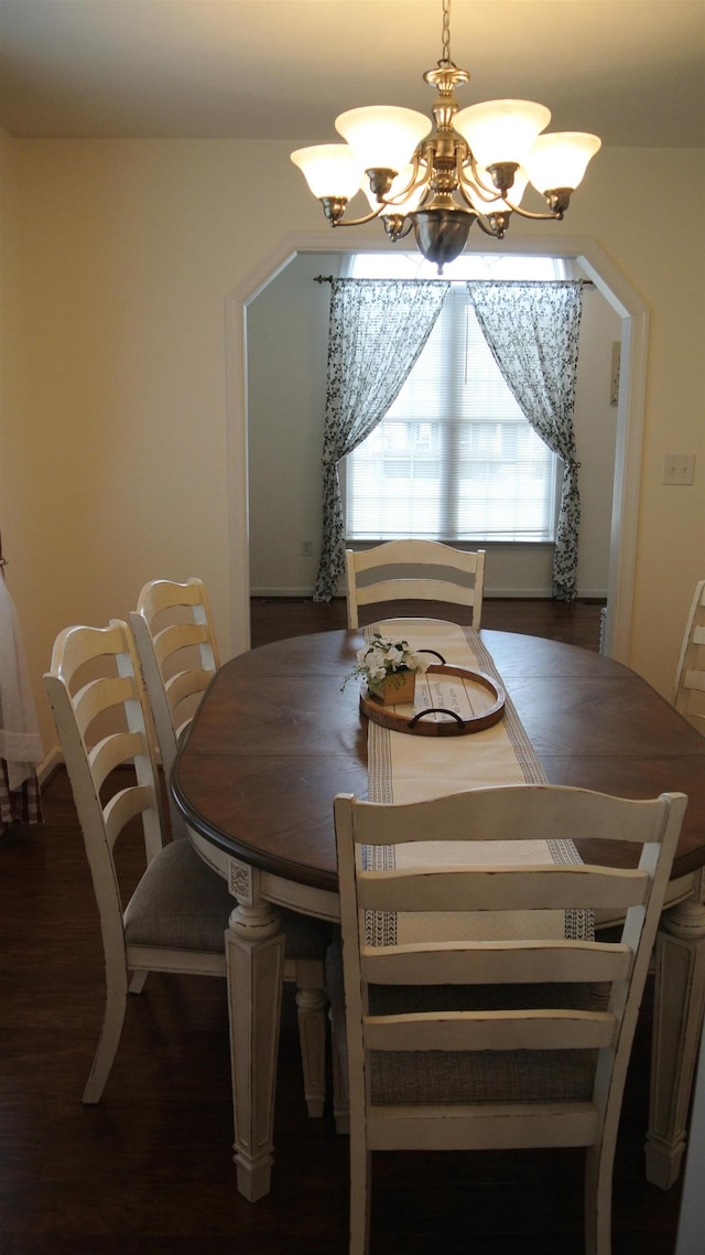 dining space with arched walkways, wood finished floors, and an inviting chandelier