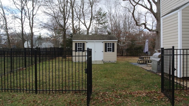 view of yard featuring a gate, a fenced backyard, an outdoor structure, and a storage shed