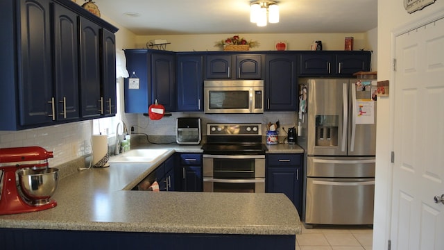 kitchen with tasteful backsplash, appliances with stainless steel finishes, a peninsula, a sink, and light tile patterned flooring