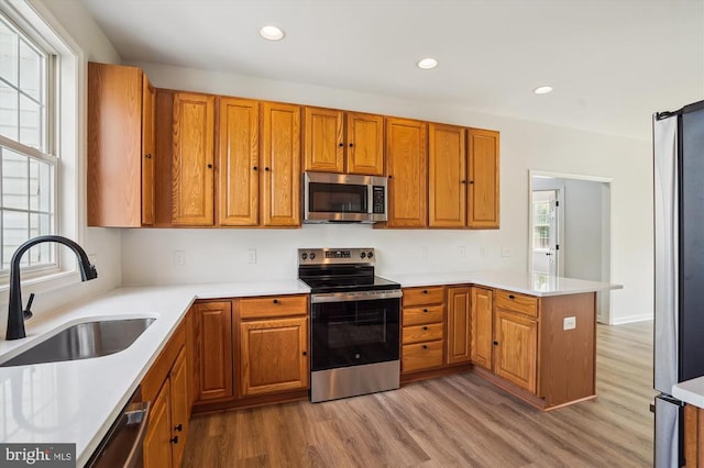 1118 Virginia Ave, Culpeper, VA 22701 - kitchen featuring appliances with stainless steel finishes, light wood-type flooring, a peninsula, brown cabinetry, and recessed lighting