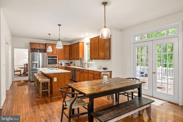 kitchen featuring appliances with stainless steel finishes, light countertops, light wood finished floors, and a kitchen island