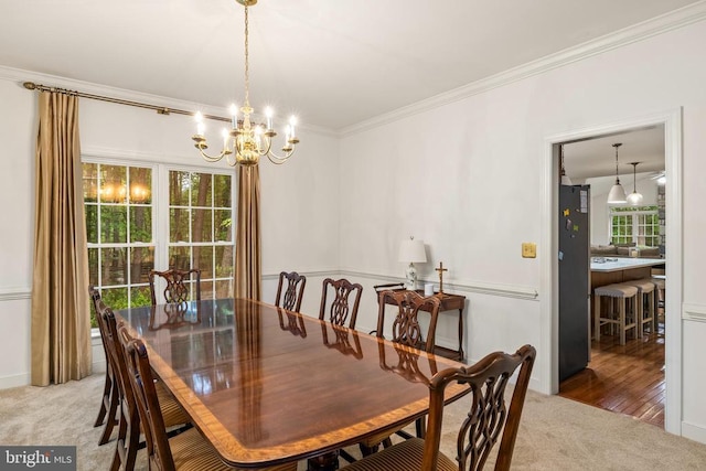 carpeted dining room featuring a chandelier and crown molding