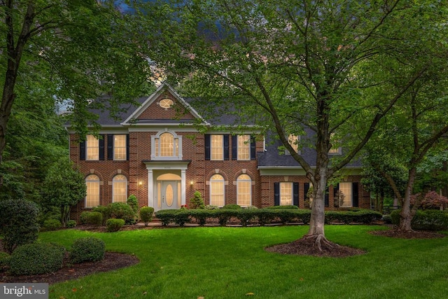 colonial-style house featuring a front lawn and brick siding