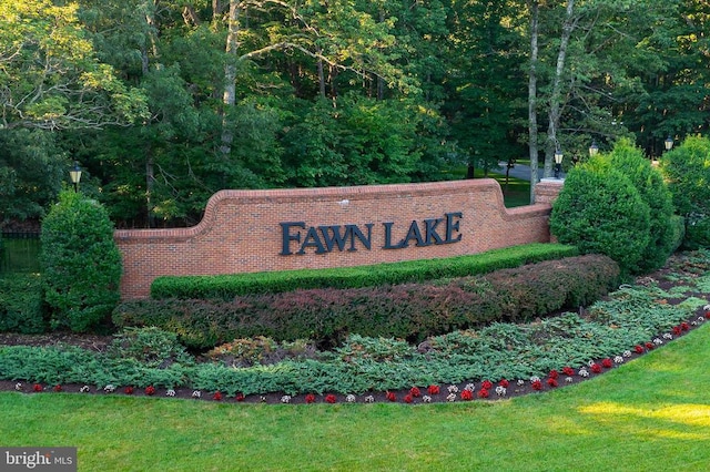 community / neighborhood sign featuring a yard and a view of trees
