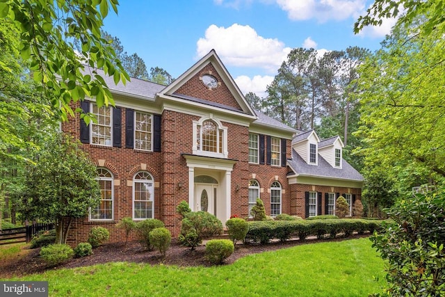 colonial inspired home with brick siding and a shingled roof
