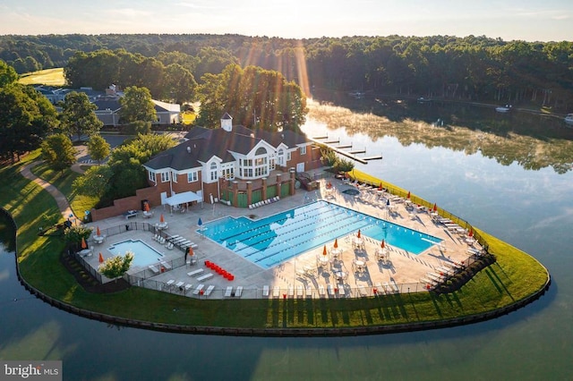 bird's eye view of a heavily wooded area, a pool, and a nearby body of water