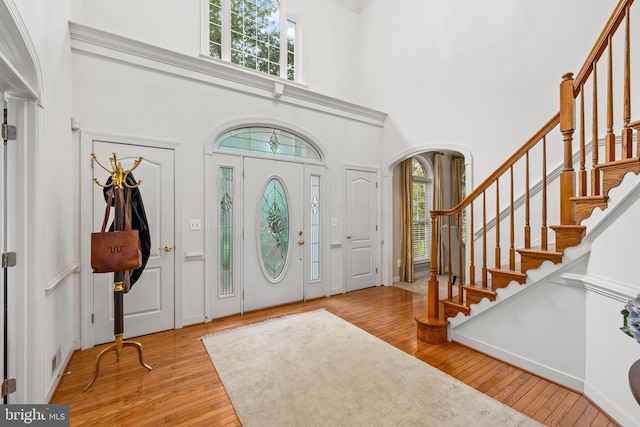 entrance foyer featuring a high ceiling, stairs, hardwood / wood-style floors, and arched walkways
