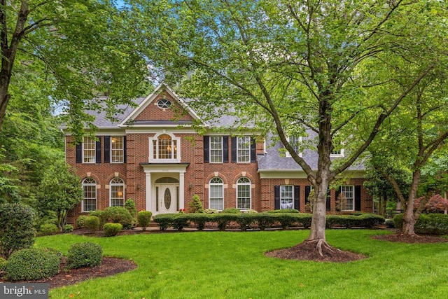 colonial-style house with brick siding and a front lawn
