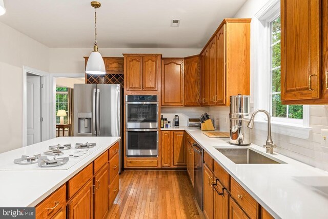 kitchen featuring stainless steel appliances, a sink, plenty of natural light, and light countertops