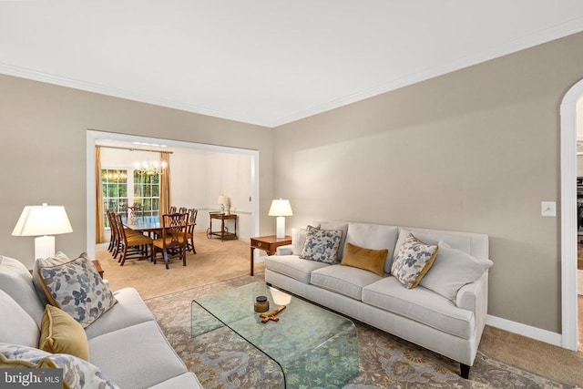 carpeted living room featuring a chandelier, ornamental molding, arched walkways, and baseboards