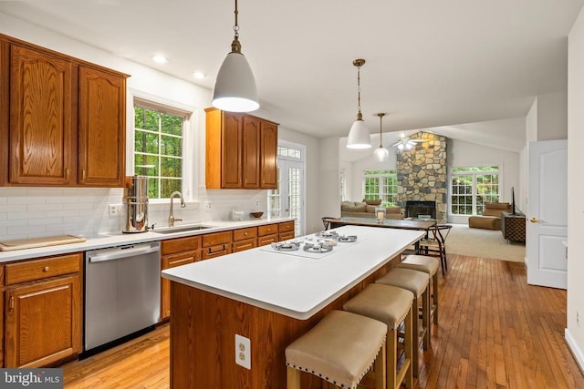 kitchen featuring dishwasher, white gas cooktop, a sink, a center island, and a kitchen breakfast bar