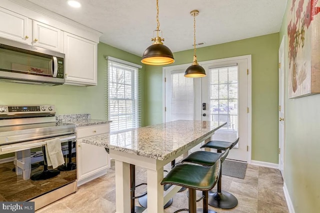 4 Brumback Ave, Luray, VA 22835 - kitchen featuring appliances with stainless steel finishes, white cabinets, a breakfast bar, light stone countertops, and pendant lighting