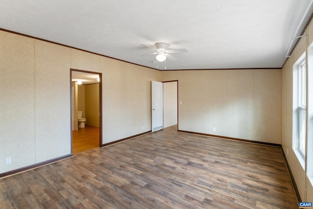 unfurnished bedroom featuring multiple windows, ensuite bath, wood finished floors, and ornamental molding