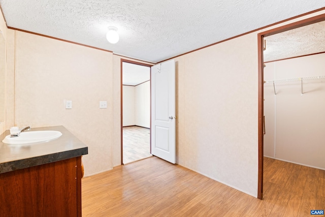 bathroom with ornamental molding, vanity, a textured ceiling, and wood finished floors