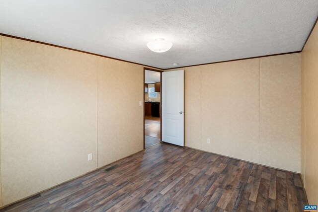 spare room with ornamental molding, a textured ceiling, dark wood-type flooring, and visible vents