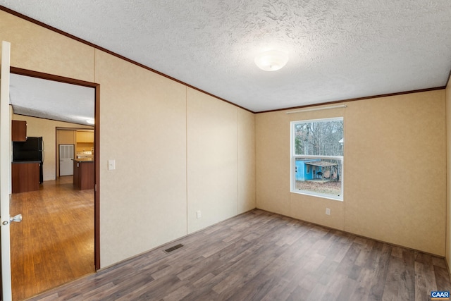unfurnished room featuring crown molding, visible vents, and wood finished floors