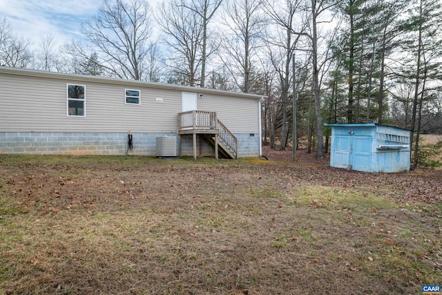 rear view of house with central air condition unit, an outdoor structure, a shed, and crawl space