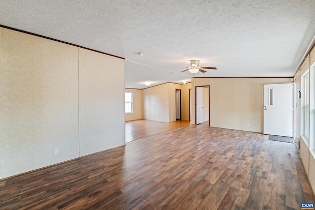 unfurnished living room featuring ornamental molding, a textured ceiling, a ceiling fan, and wood finished floors