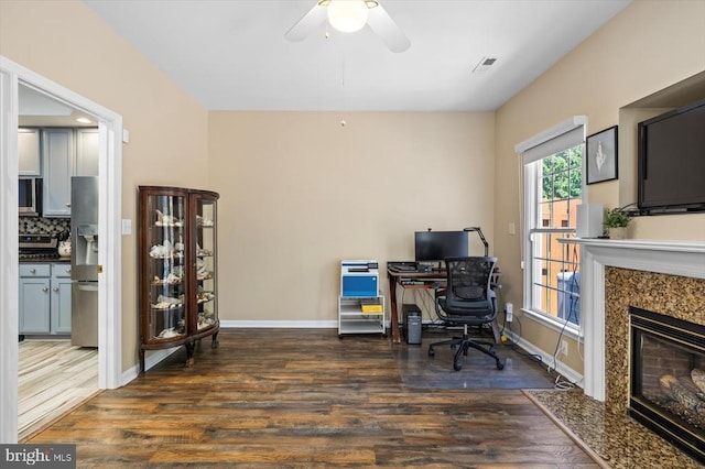 home office featuring wood finished floors, a ceiling fan, baseboards, and a fireplace