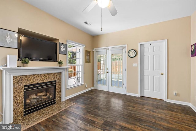unfurnished living room featuring wood finished floors, baseboards, ceiling fan, and a premium fireplace